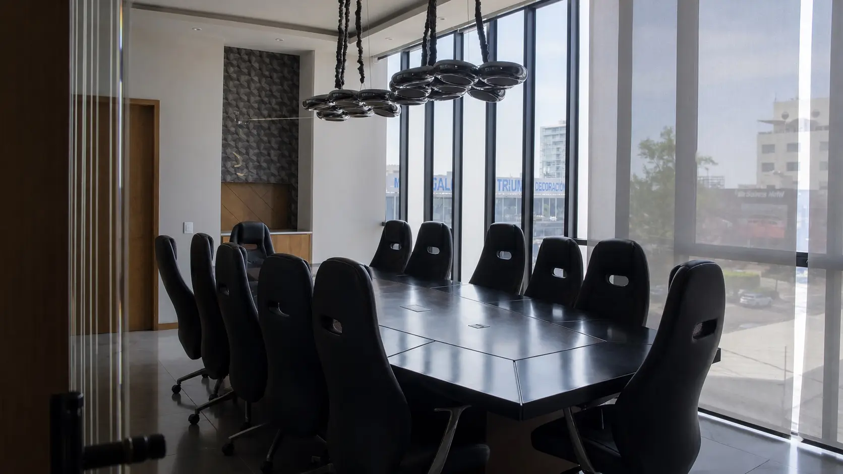 Sala de consejo de las oficinas de Concordia Patrimonial: mesa modular para doce personas, sillones negros y ventanales de piso a techo con vista a la avenida.